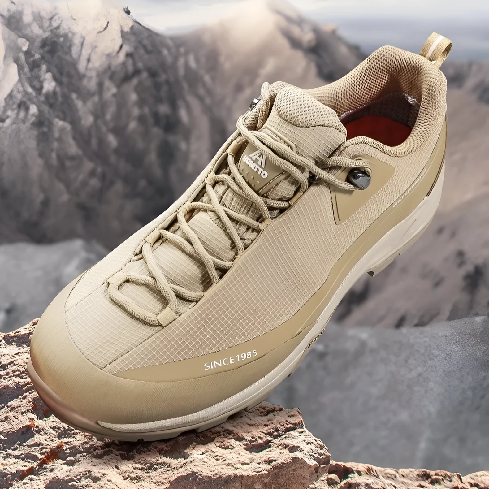 Men's low-top hiking boots in dark grey with round toe and front lace-up design on a rocky trail.