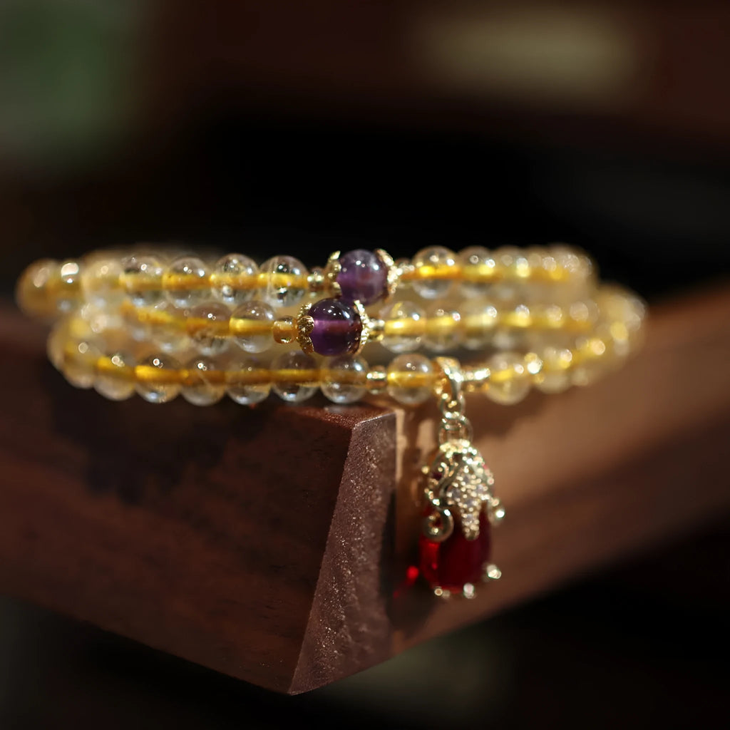 Natural gold rutilated quartz bracelet with three gold rings on wrist