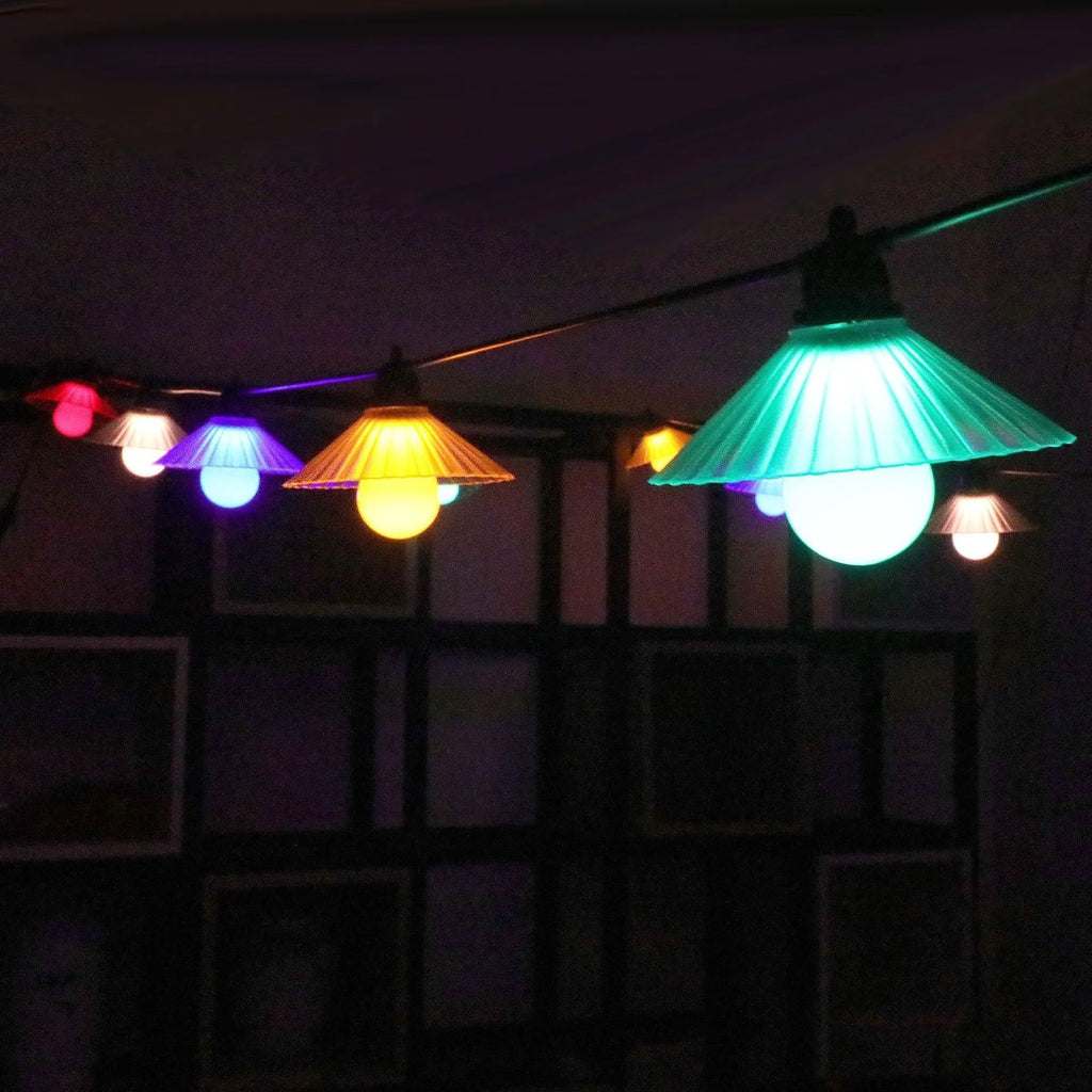 Outdoor LED string lights with flower-shaped bulbs hanging in a garden, showing warm white and coloured options.