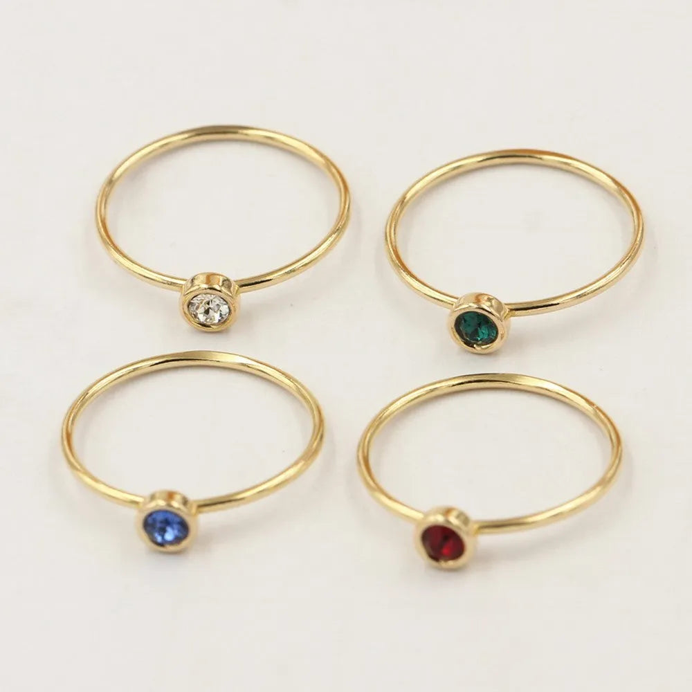 Gilded copper knuckle ring with a blue cubic zirconia stone on a model's hand.