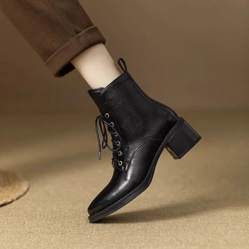 Women's black pointed-toe ankle boots with a short tube and block heel on a plain background