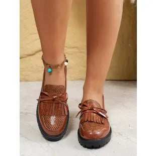 Women's brown and black loafers with a decorative bow on the front.