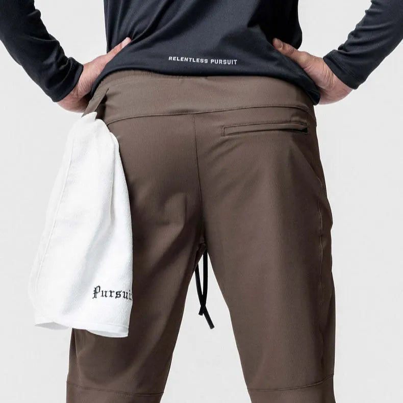 Man wearing dark grey loose-fit ankle-tied running pants made from quick-drying polyester fabric.