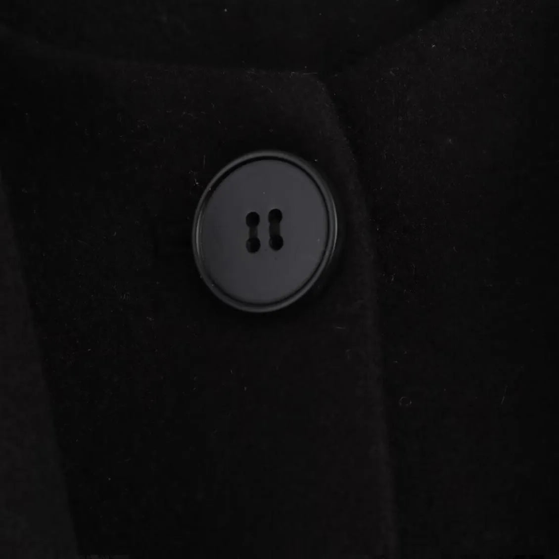 Women's long black polyester blend overcoat with a detachable artificial fur collar, showing pocket detail and street-fashion fit.