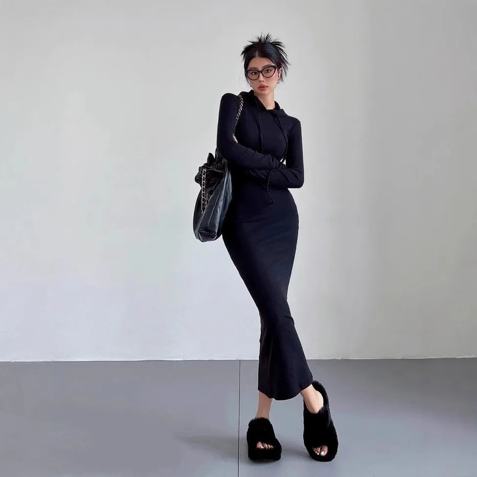 A woman wearing a grey hooded sheath dress with long sleeves and an over-the-knee length.