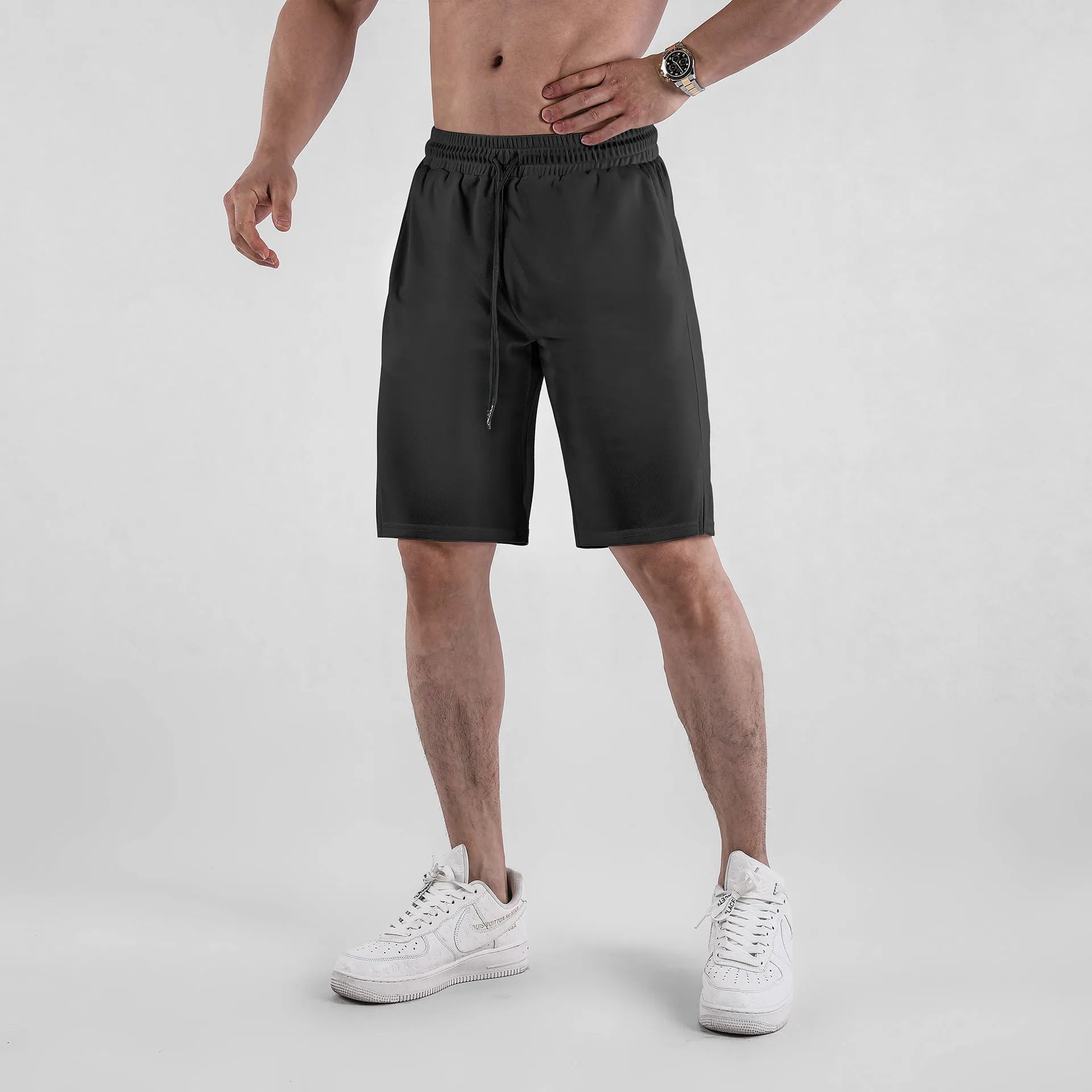 Man wearing black loose-fit quick-dry mesh fitness shorts with an elastic waistband.
