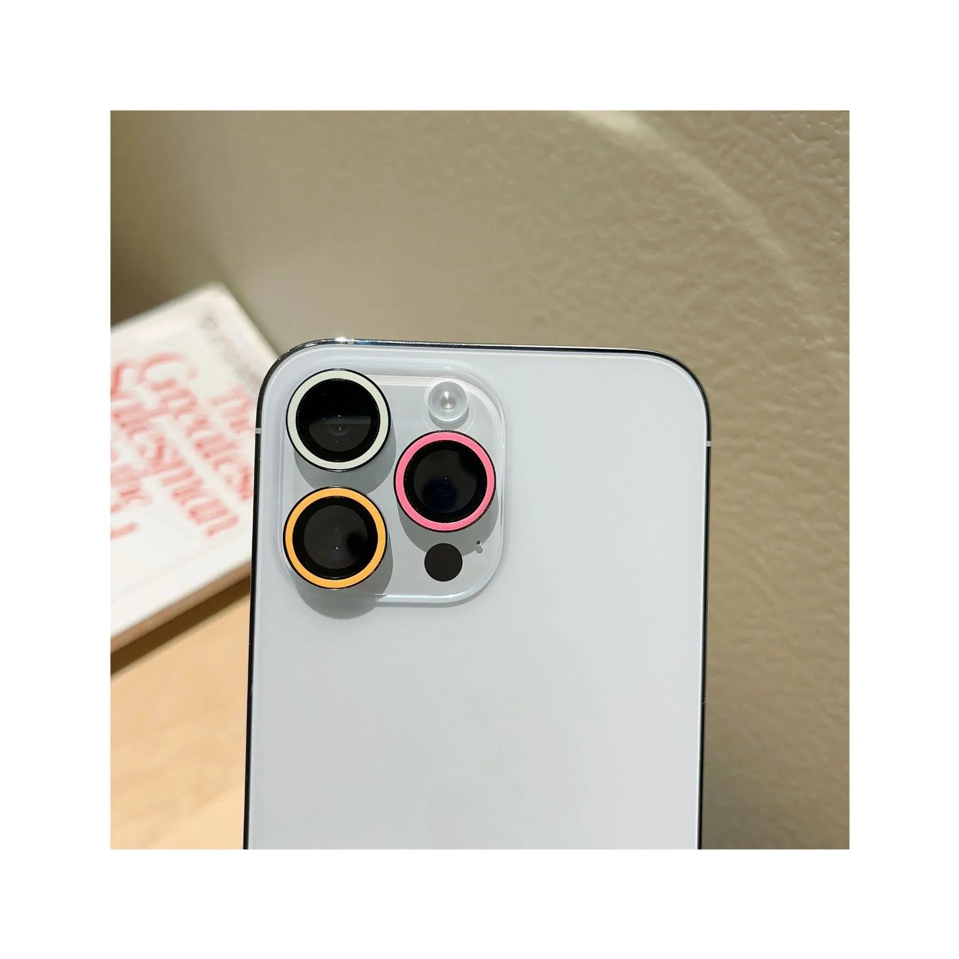 Luminous tempered glass camera lens protector for iPhone 14 Pro Max showing three-hole cutout in yellow blue pink