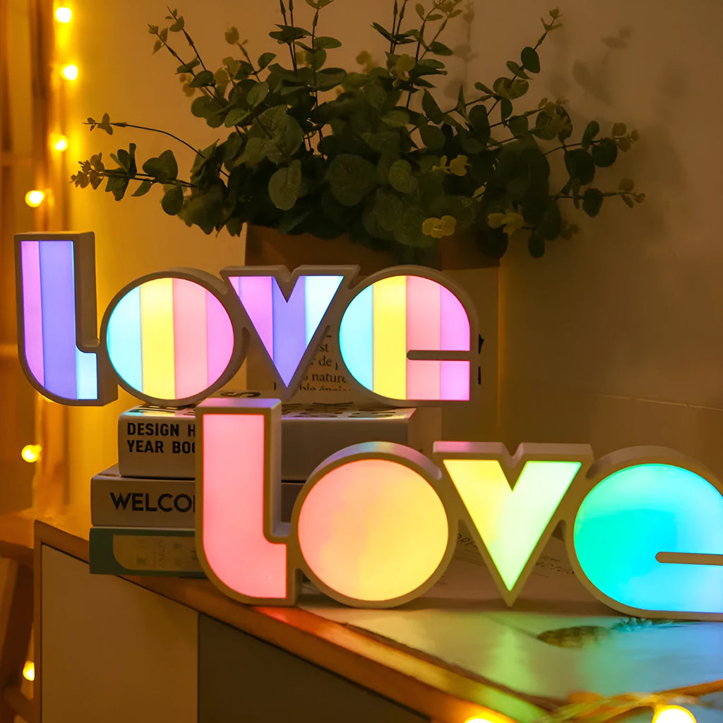 Rainbow-coloured plastic LED light spelling LOVE, standing 35.5cm tall on a table.