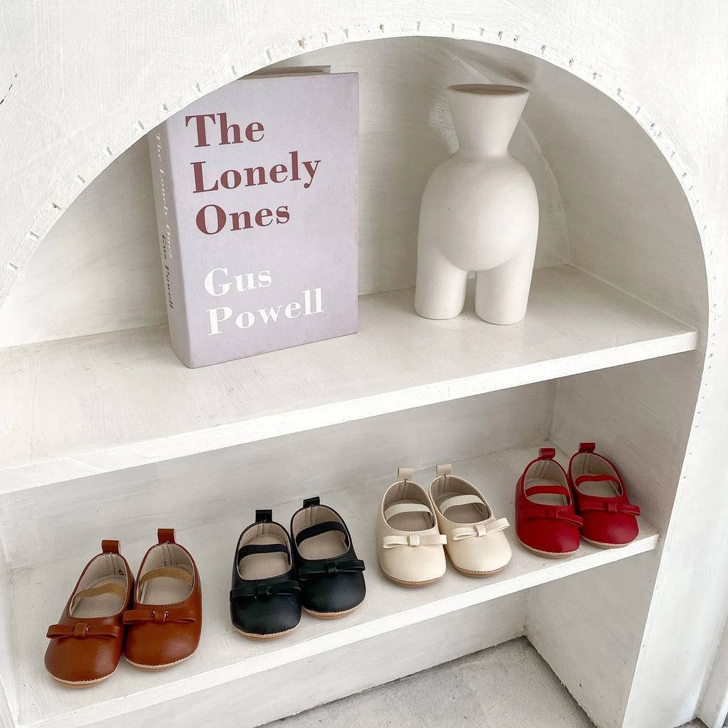 Baby shoes in white with bow detail, non-slip rubber sole, and elastic band fastening