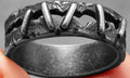 Stainless steel dark punk stitching style double ring on a finger, showing the textured design.