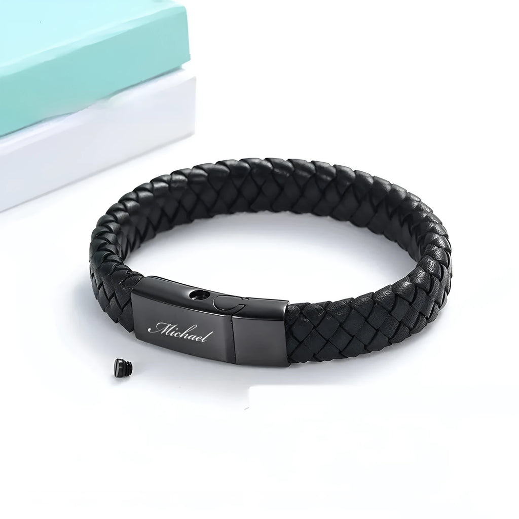 Black leather and stainless steel casket bracelet with engraved text on a gift box.