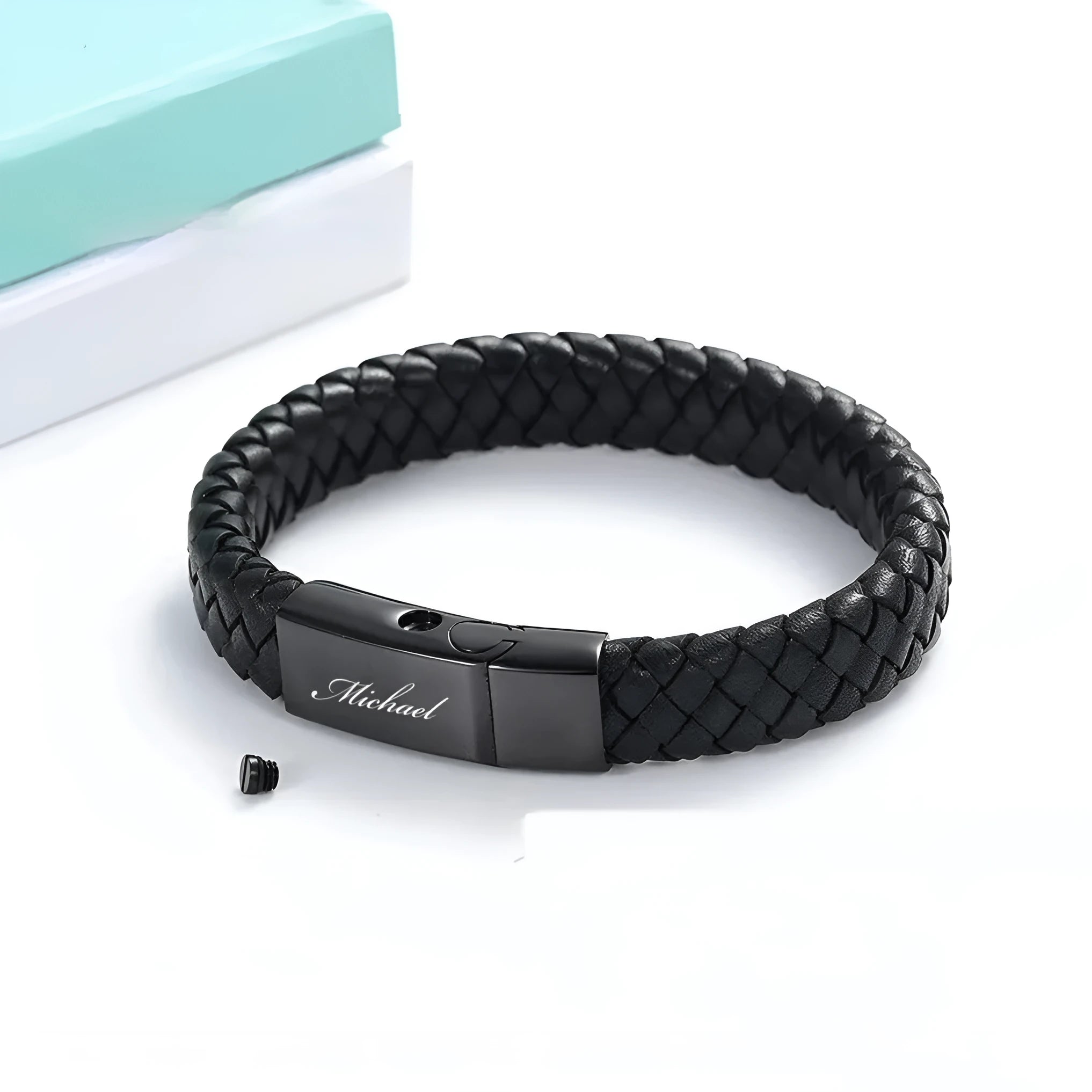 Black leather and stainless steel casket bracelet with engraved text on a gift box.