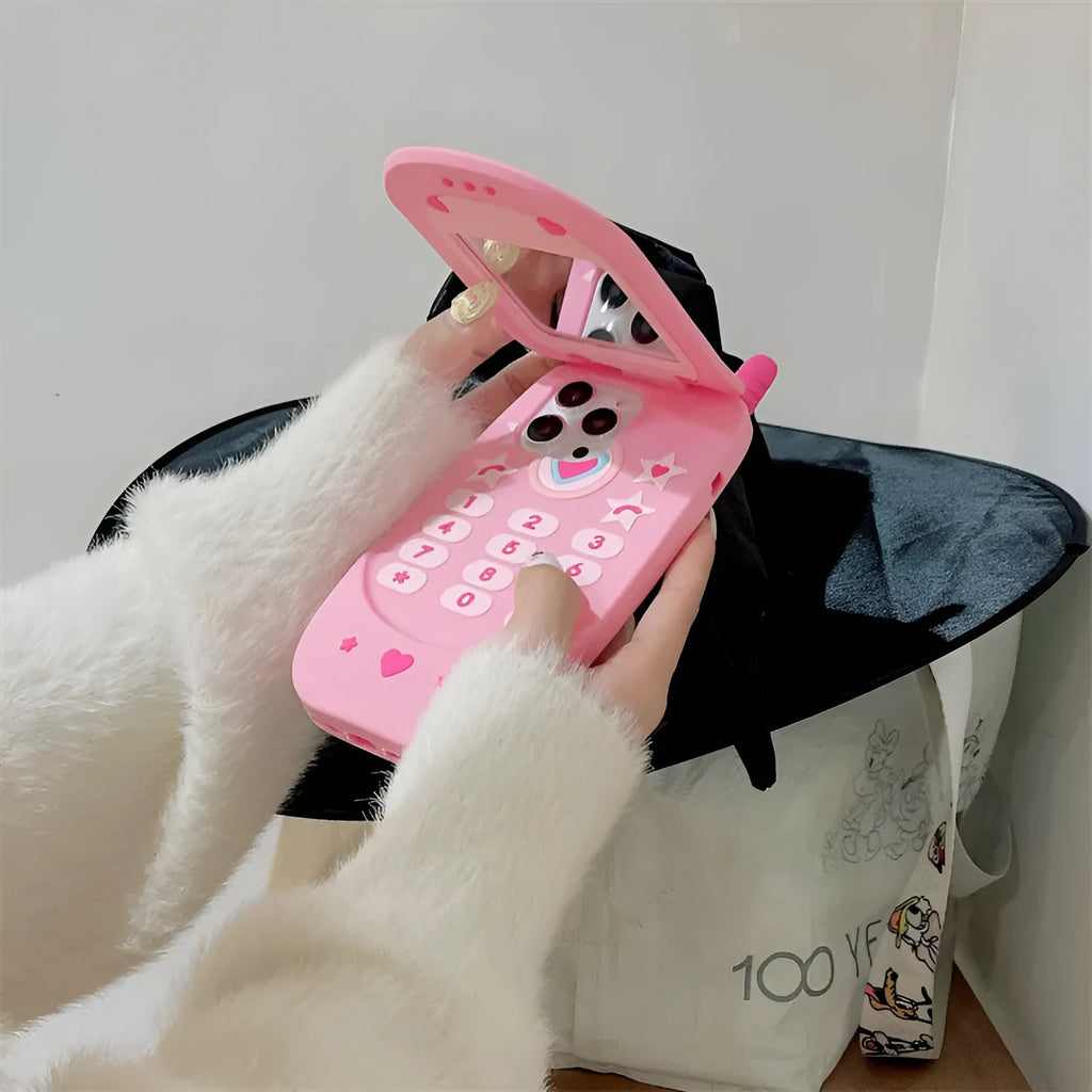 Pink silicone iPhone case shaped like a flip phone with a front mirror.