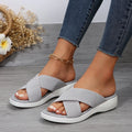 Women's black flat wedge slippers with peep toe and cross strap on a rubber sole.