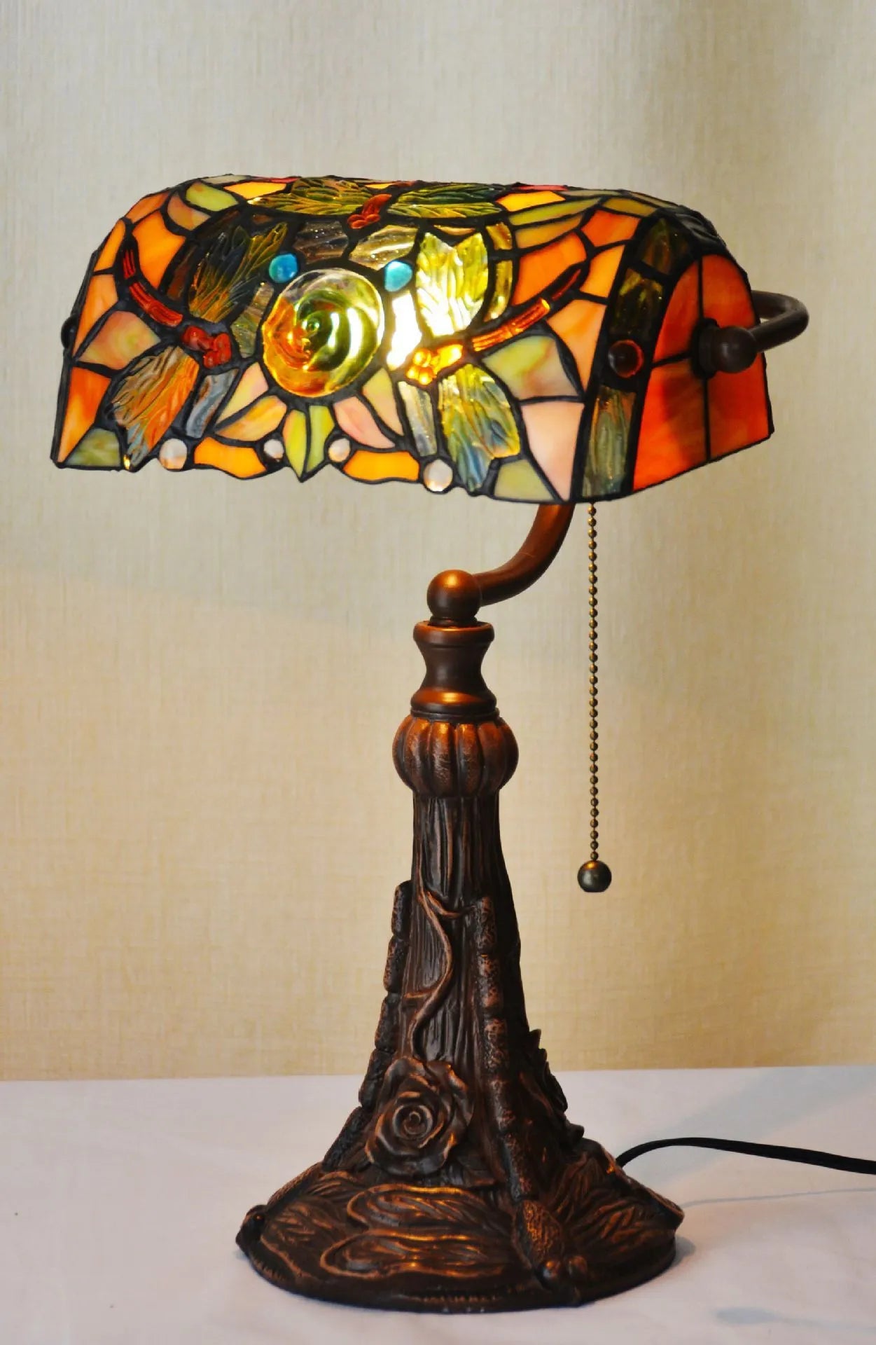Tiffany table lamp with stained glass shade on wooden desk, 36cm tall with warm lighting