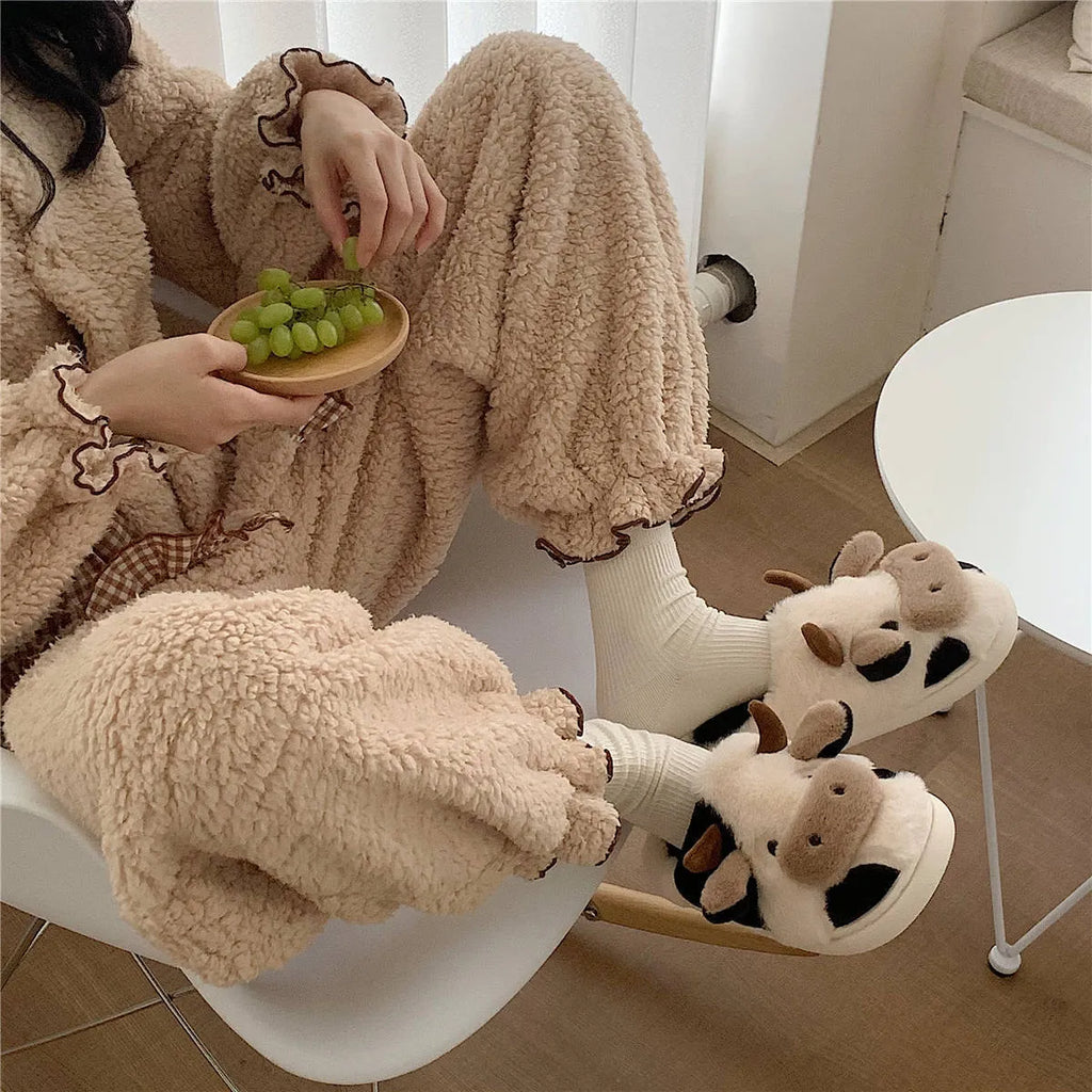 White cow print faux fur plush slippers for women with a non-slip textured sole.