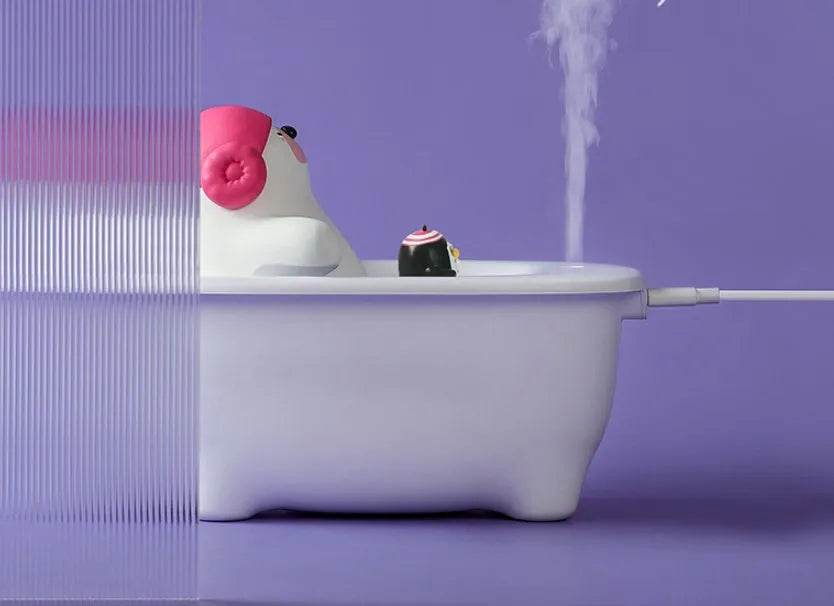 White USB air humidifier with large water tank on a desk next to a laptop.