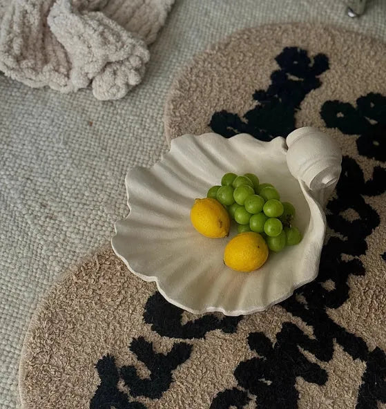 White resin shell-shaped fruit plate ornament with light luxury styling on a table.