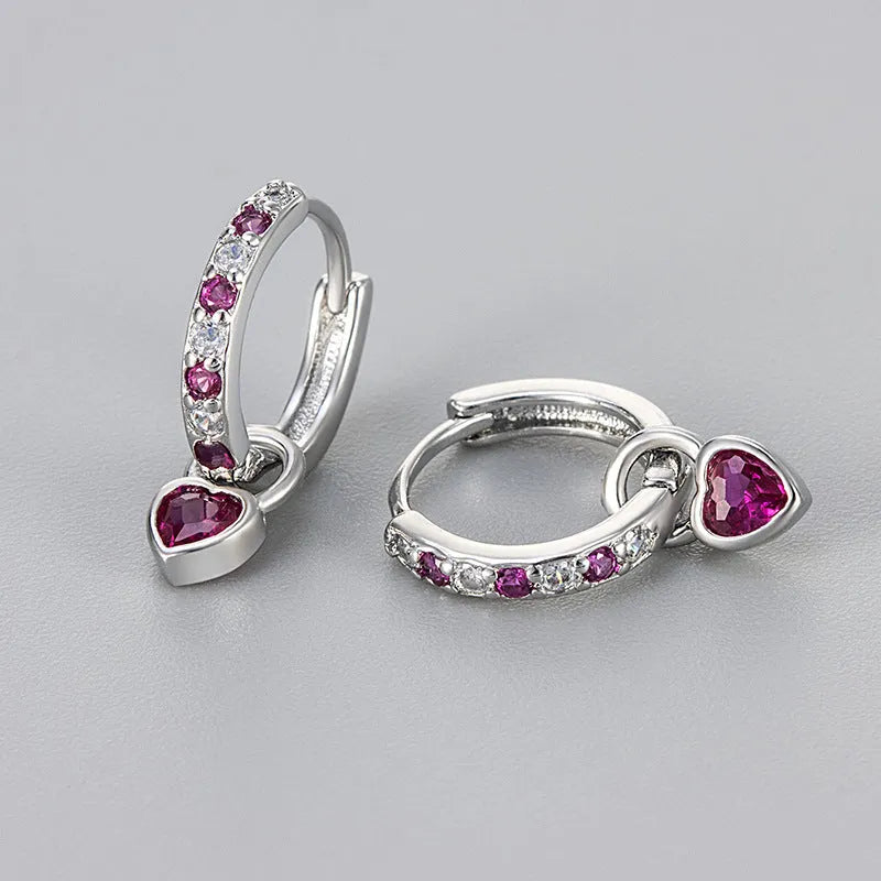 A pair of women's dangle earrings with a heart-shaped frame holding a coloured zircon stone.