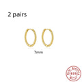 Twisted round sterling silver hoop earrings in golden and white gold colours on a plain background.