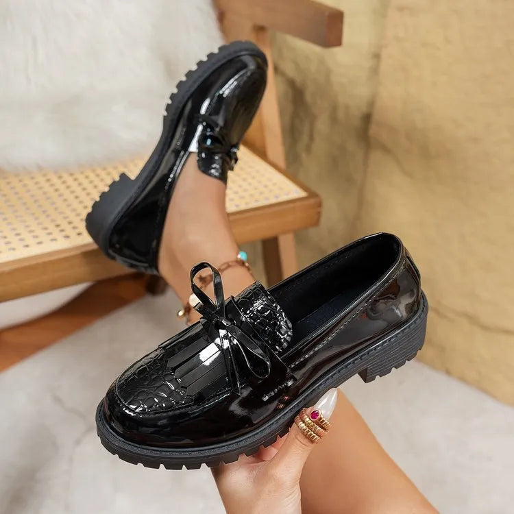 Women's brown and black loafers with a decorative bow on the front.