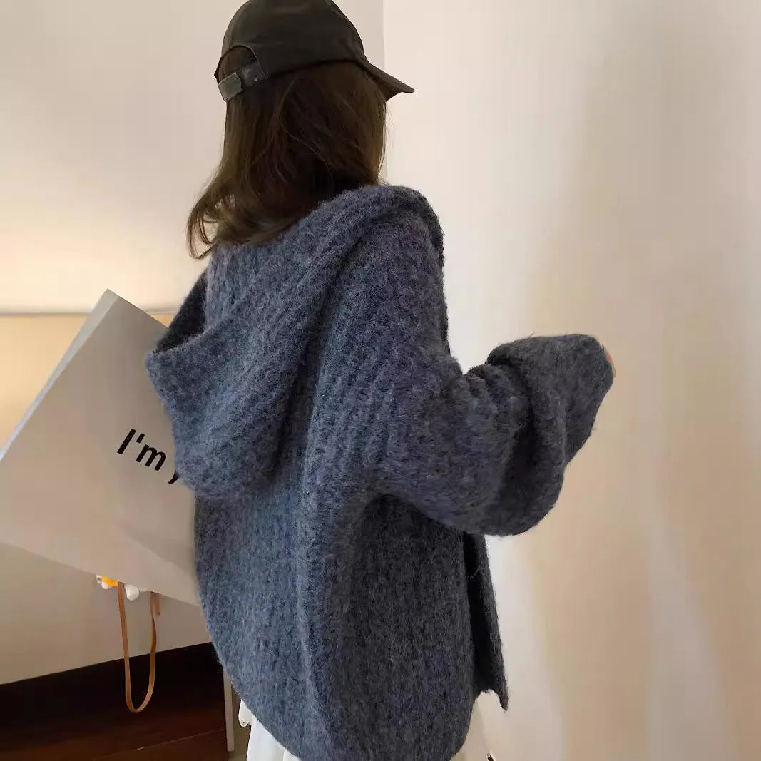 Woman wearing a dark gray retro-style hooded cardigan sweater with a loose fit.
