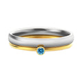 December birthstone geometric engraved ring in titanium steel with gold-coloured handle on a grey background.