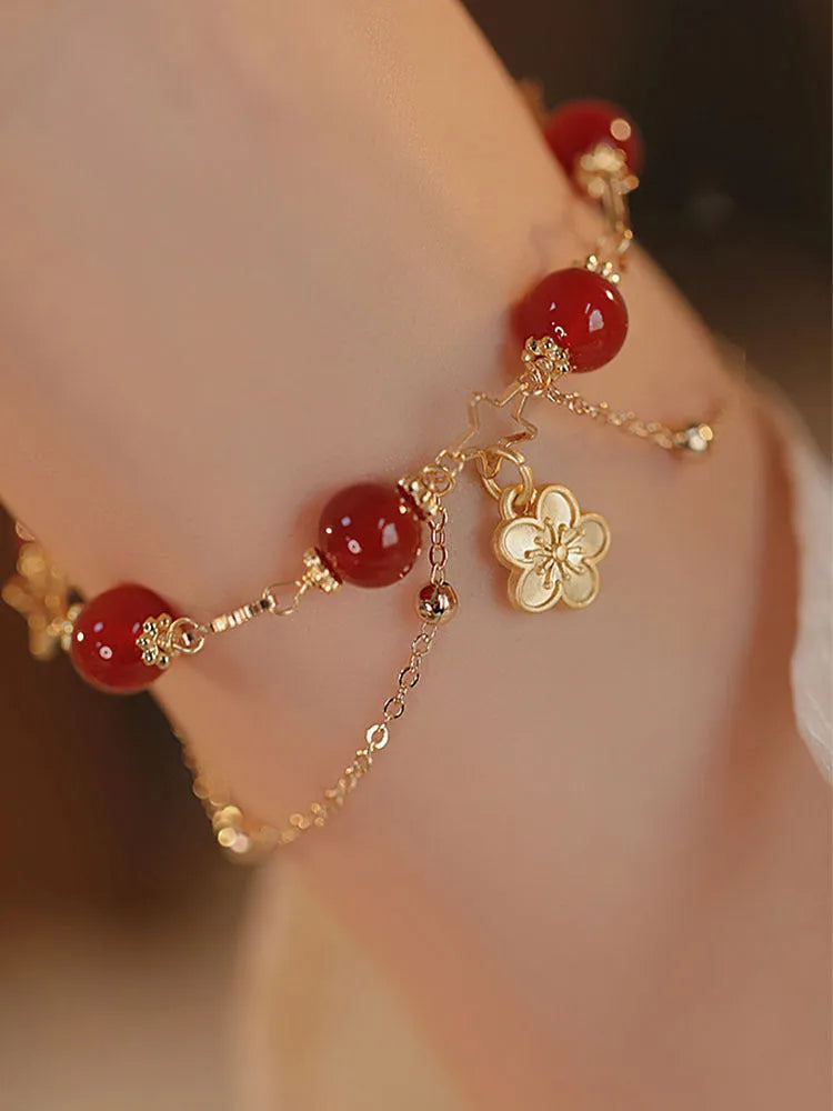 Close-up of a red agate double layer bracelet with floral and peach blossom detailing on a woman's wrist.