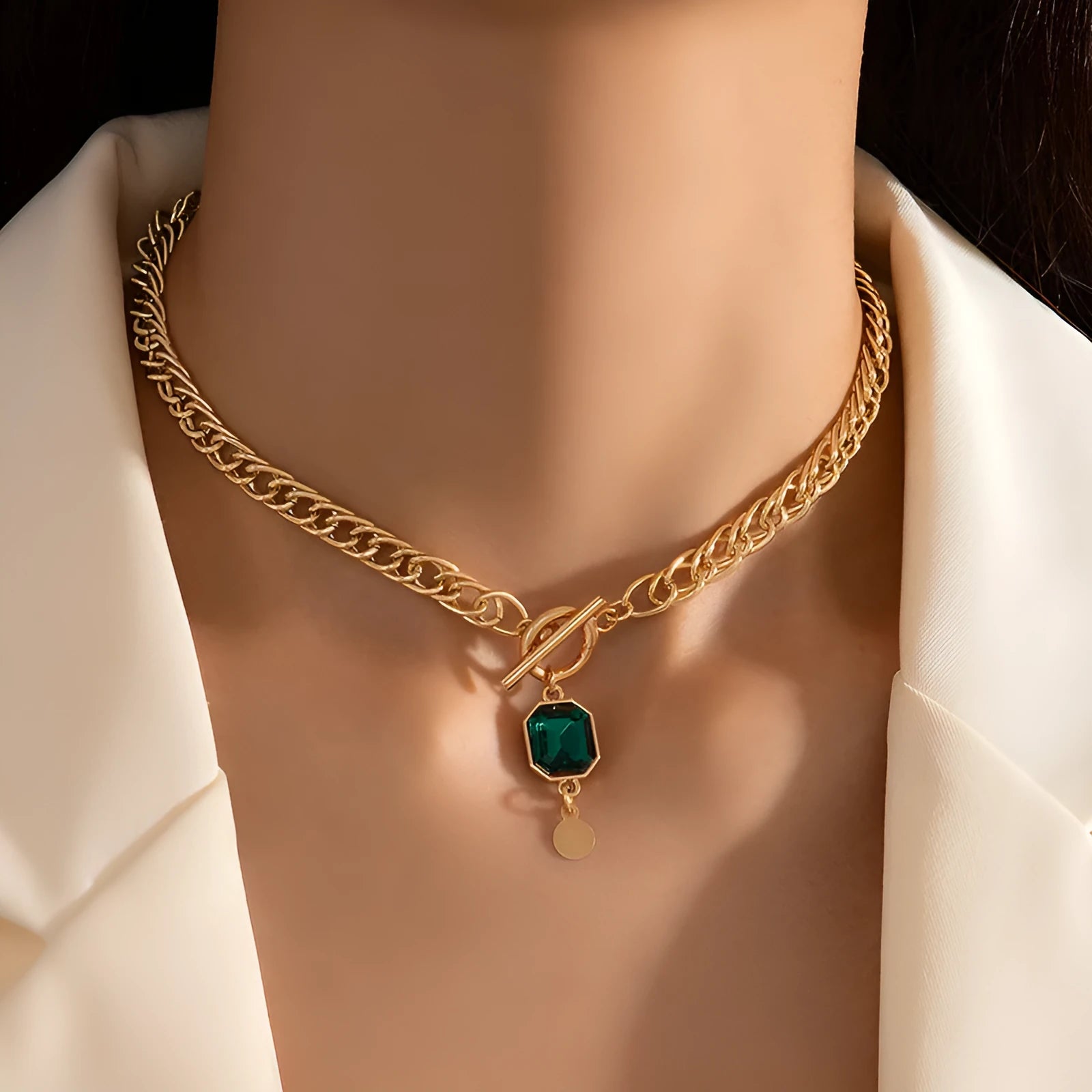 Gold electroplated titanium steel necklace with geometric round pendant containing emerald zircon accents