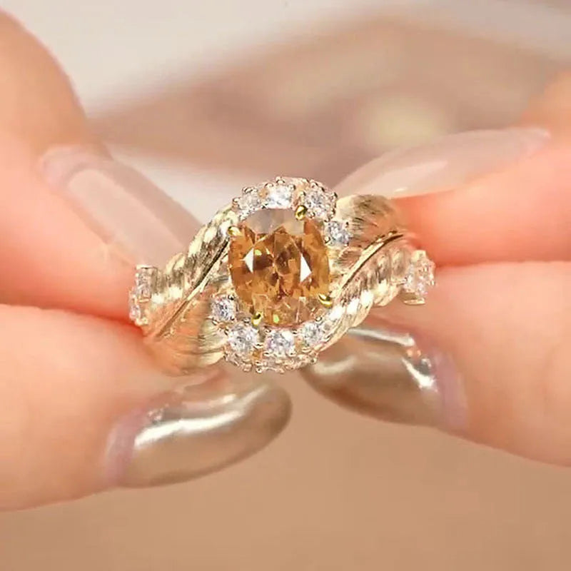 Gold-colour women's ring with a detailed embossed feather design and a central yellow zircon stone on a geometric copper band.