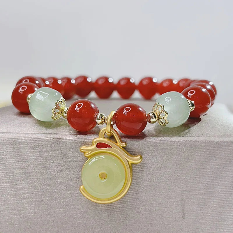 Handmade red agate women's bracelet with dragon design on a wrist.