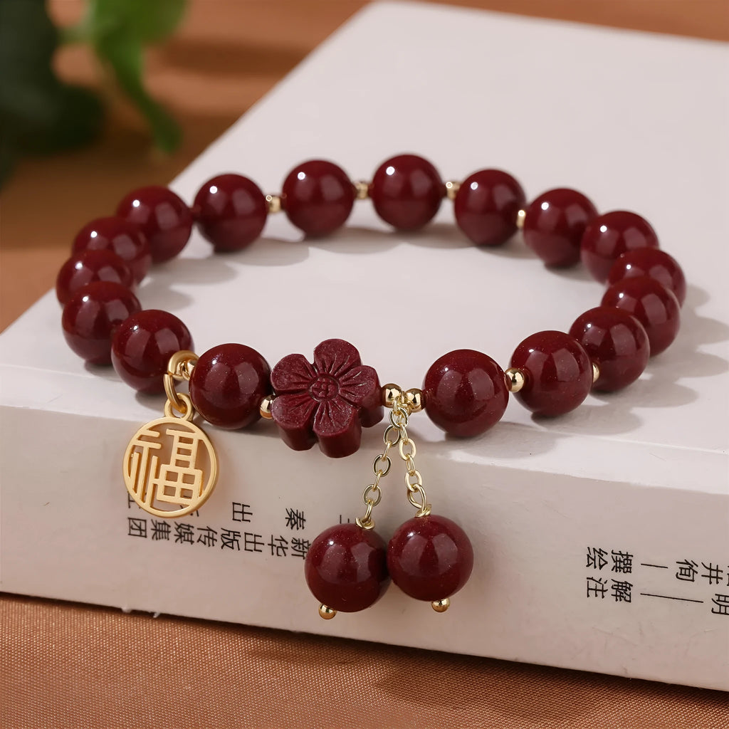 Close-up of a purple gold sand cinnabar bracelet with a fu character charm and adjustable tassel.
